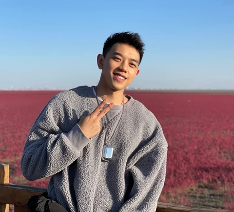 李星明在蓝天和红色地面前微笑的个人照